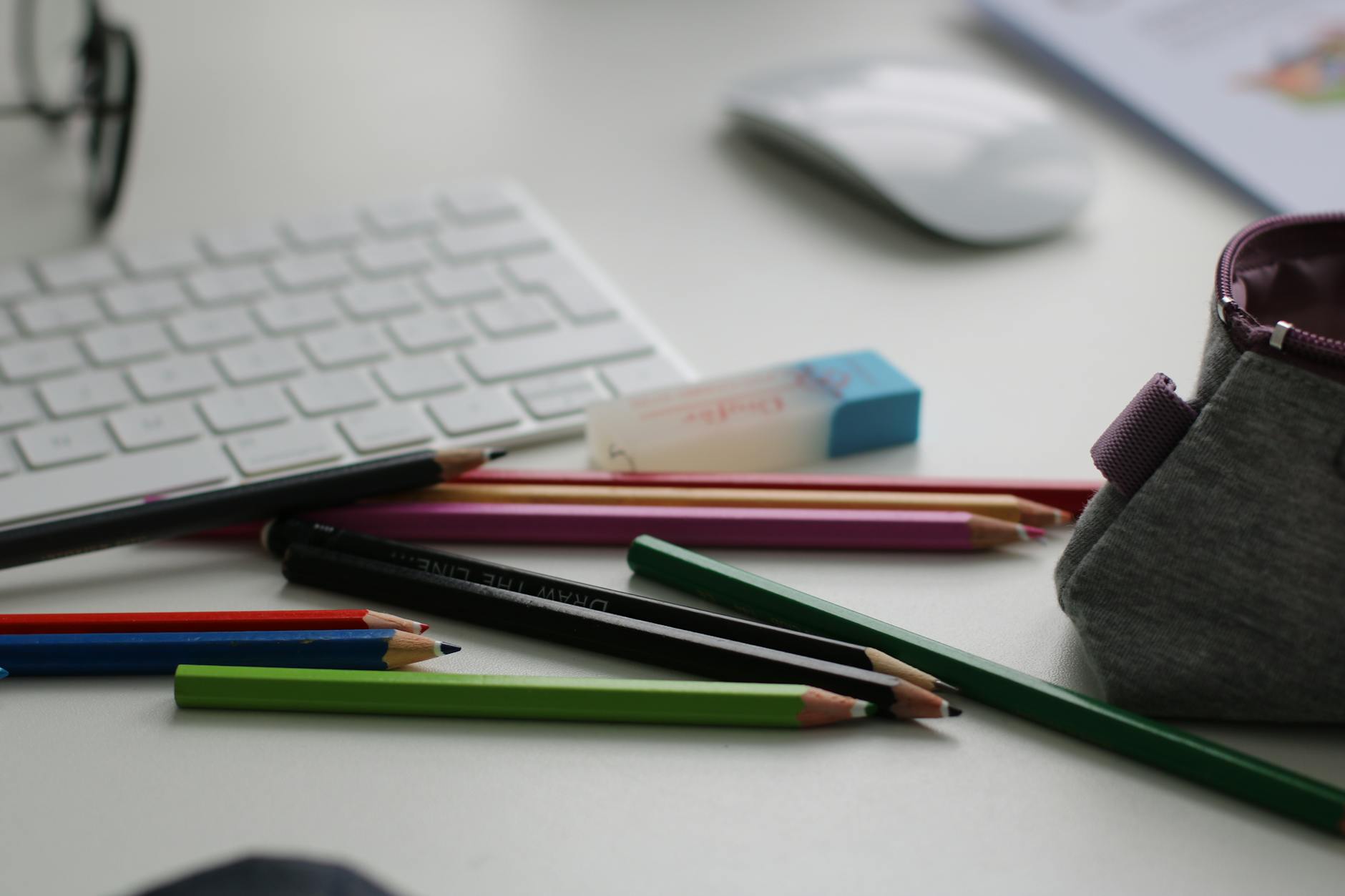 shallow focus photography of assorted pencils near apple keyboard and mouse